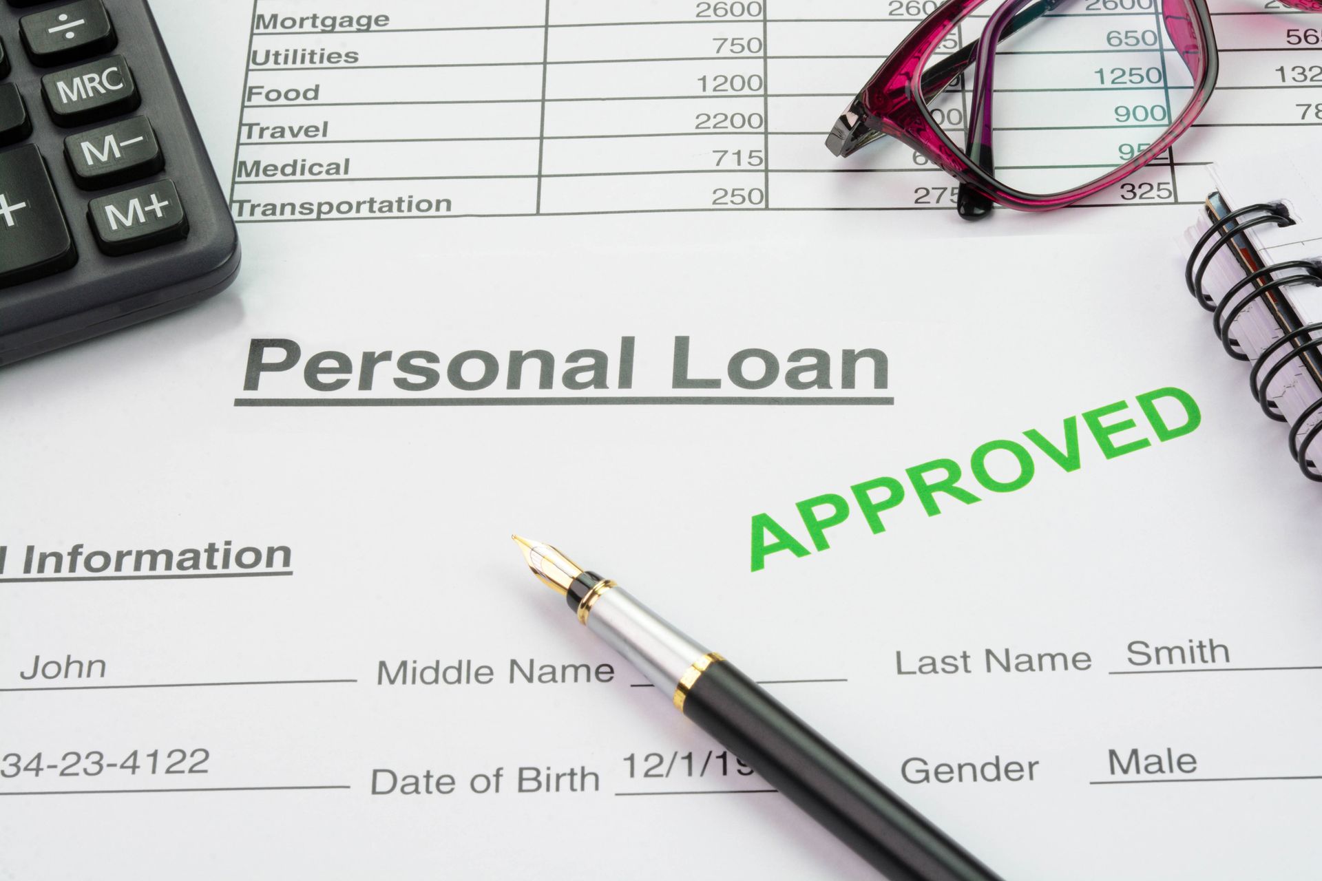 An approved personal loan form with a pen and calculator