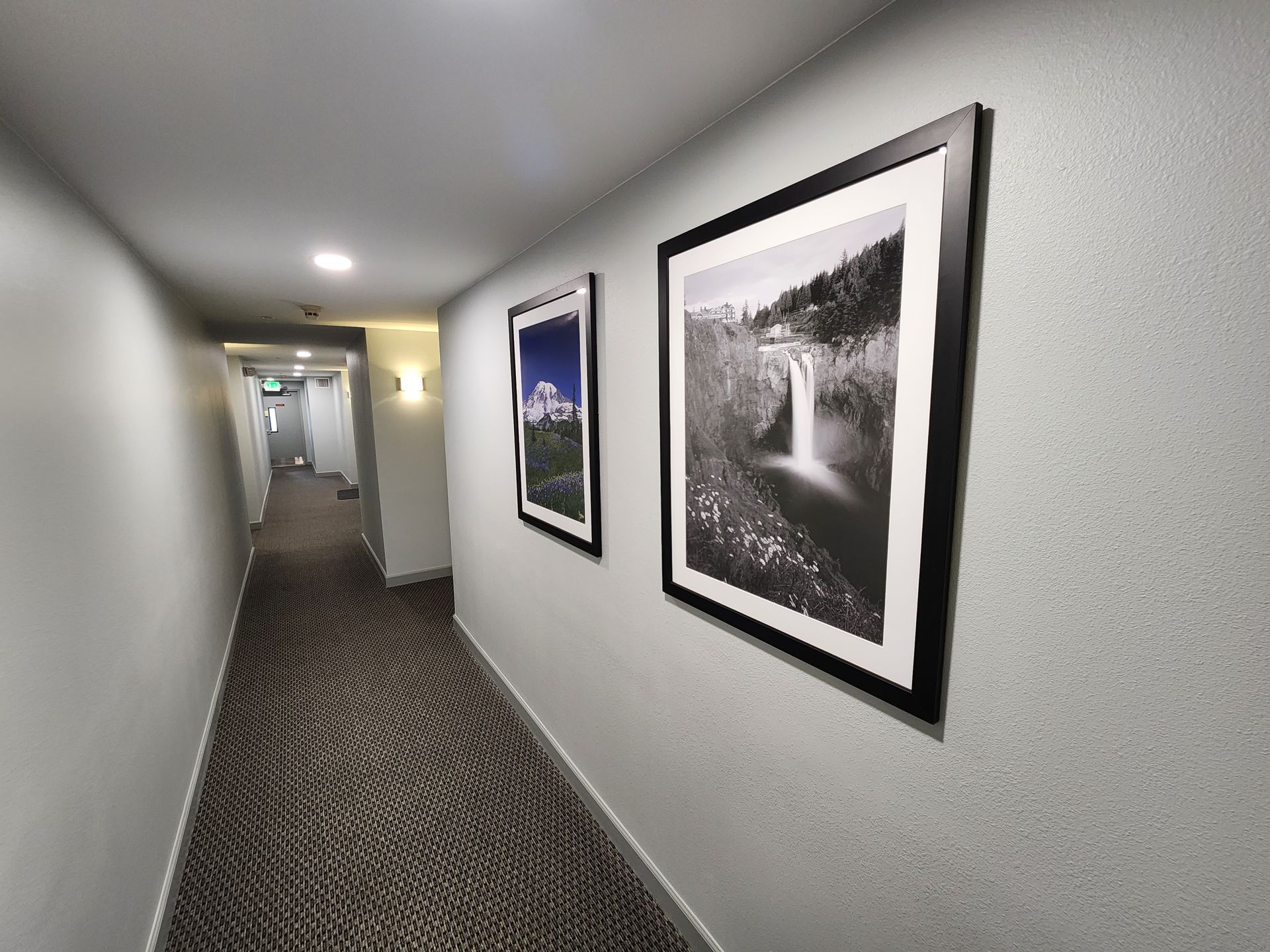 Hallway with framed art, patterned carpet, and recessed lighting.