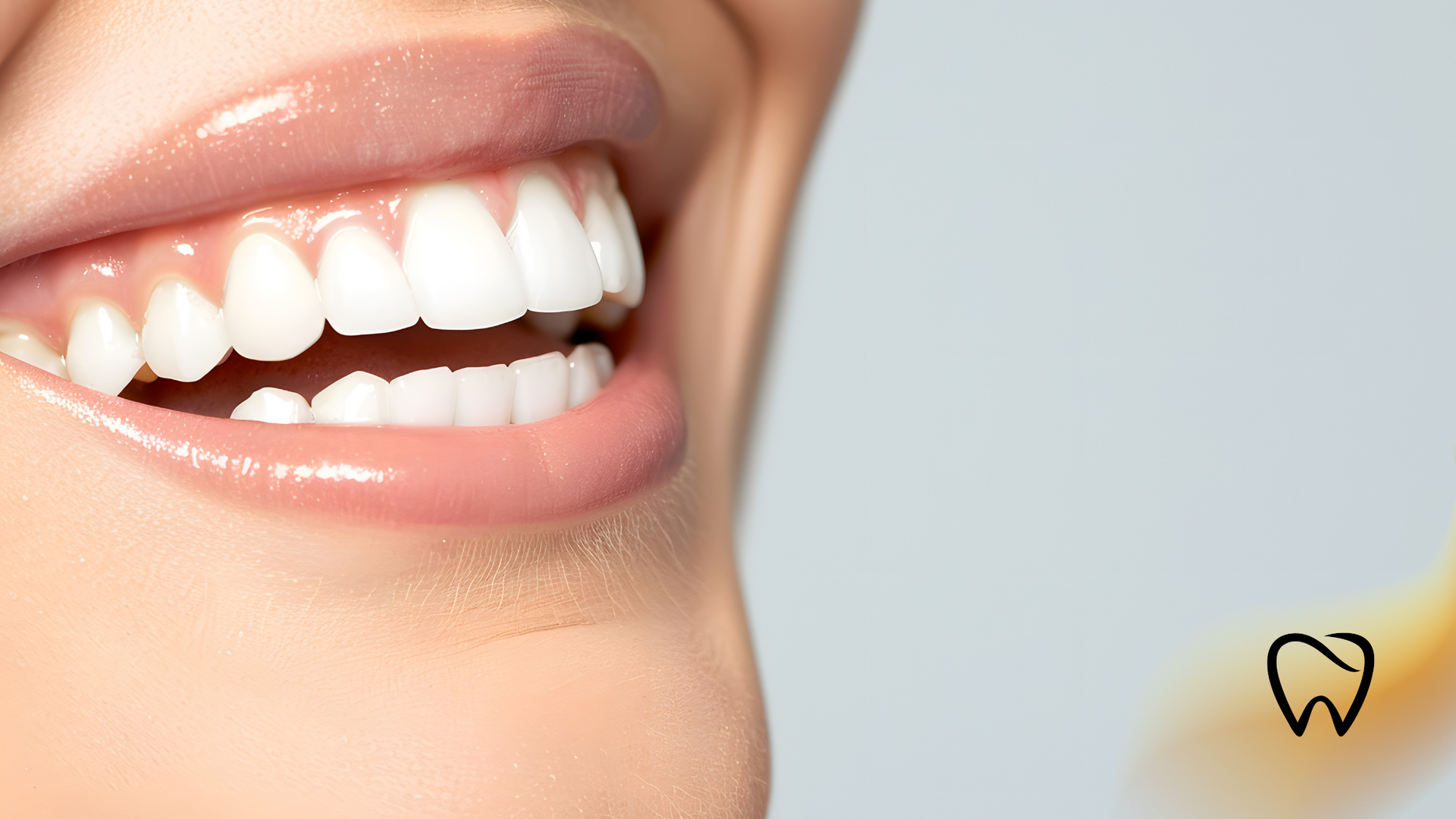 Close-up of a smiling person with bright white teeth, smooth pink lips, and a neutral background.