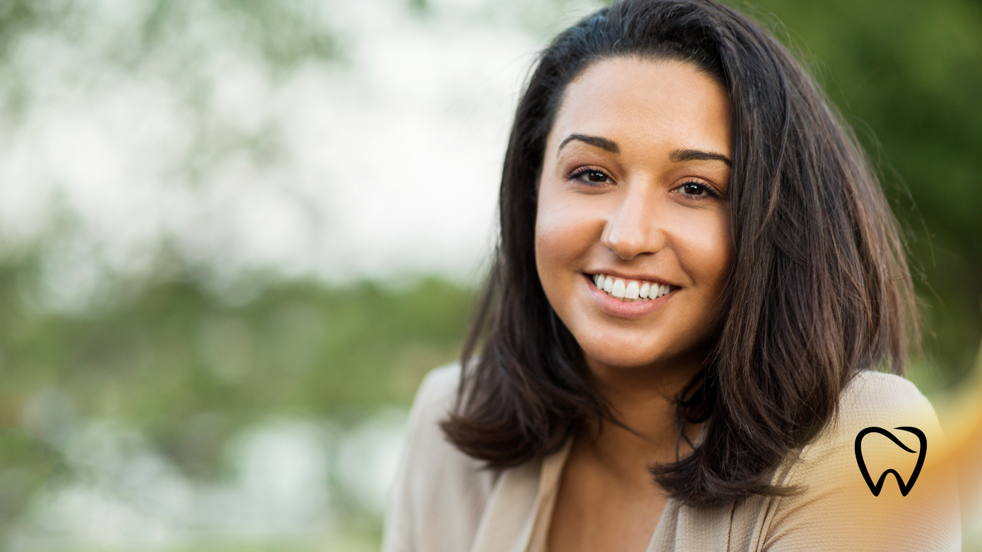 Woman with short dark hair smiles outdoors.
