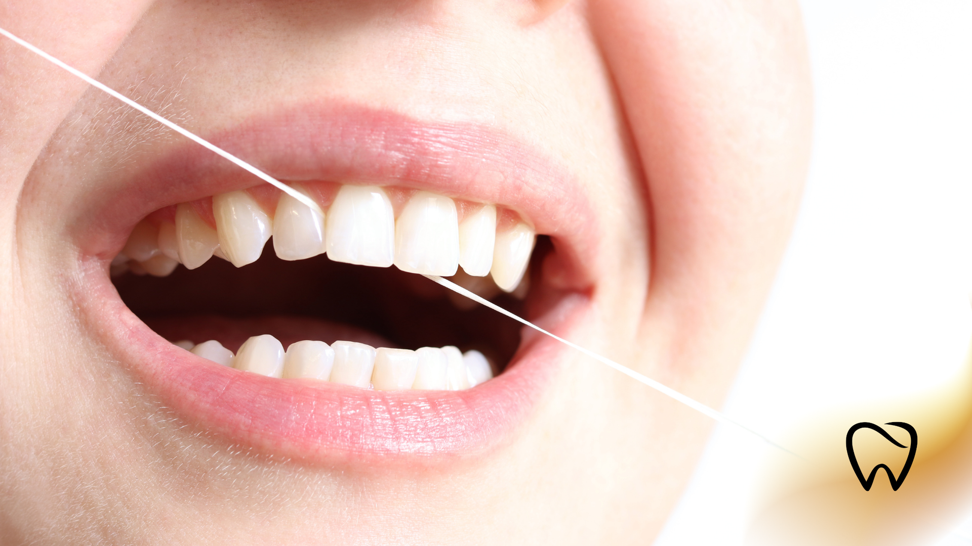 Person flossing teeth, close-up. Shows healthy white teeth with floss between them.