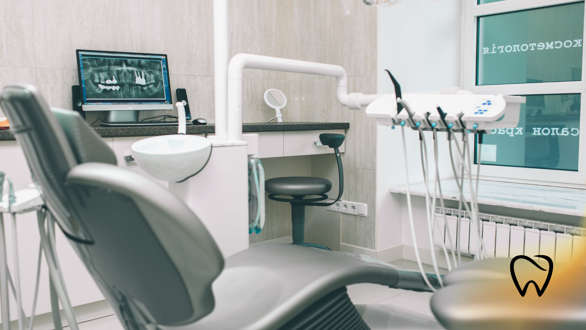 Dental office interior with patient chair, equipment, and a monitor displaying dental x-rays.