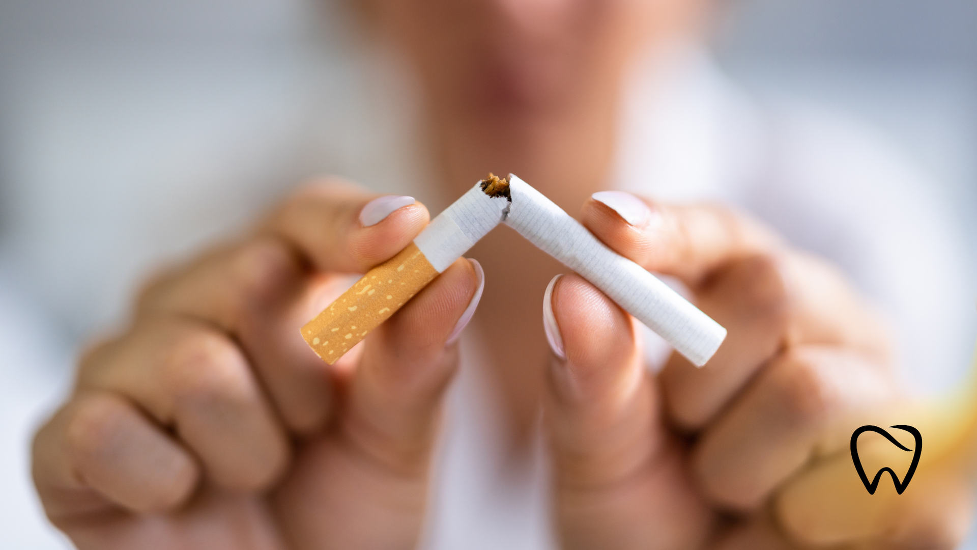 Person breaking a cigarette in half, signifying quitting smoking.