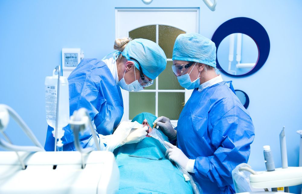 Two medical professionals in a dental surgery performing a procedure on a patient.