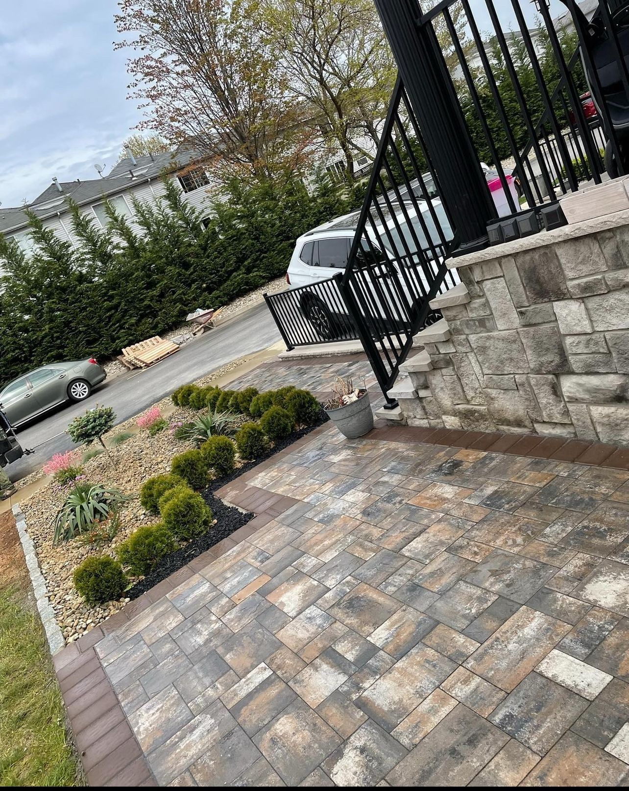 A brick walkway with a railing and a car parked on the side of the road.