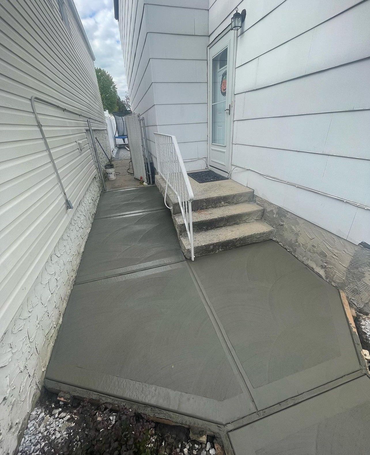 A concrete walkway with stairs leading up to a house.
