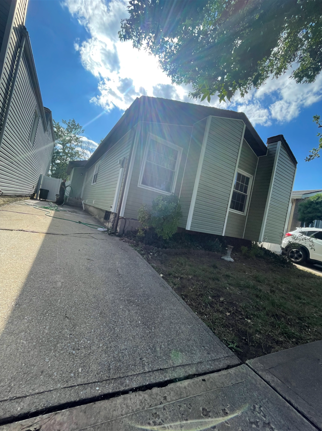 A small house with a car parked in front of it on a sunny day.