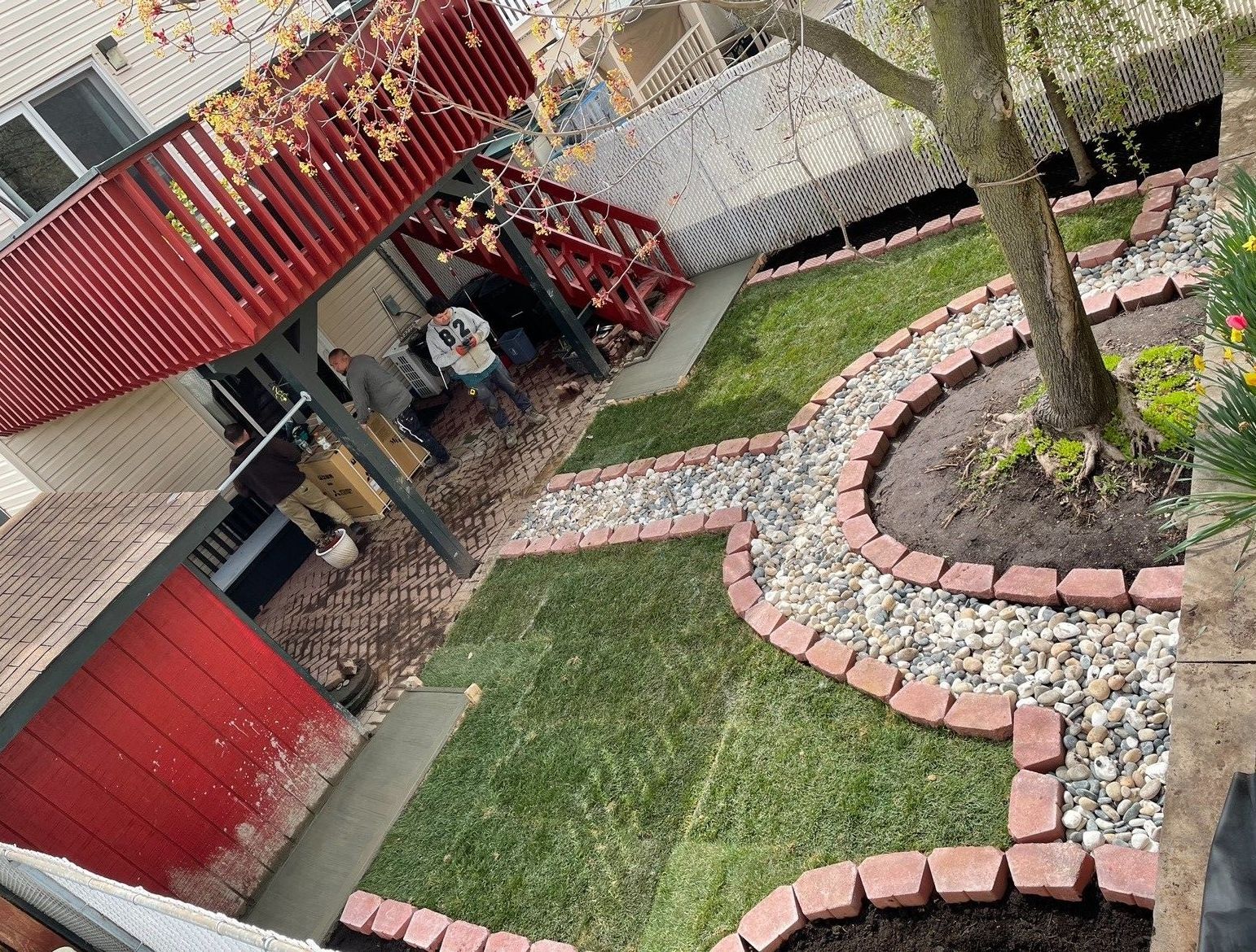 An aerial view of a backyard with a brick walkway and a red deck.