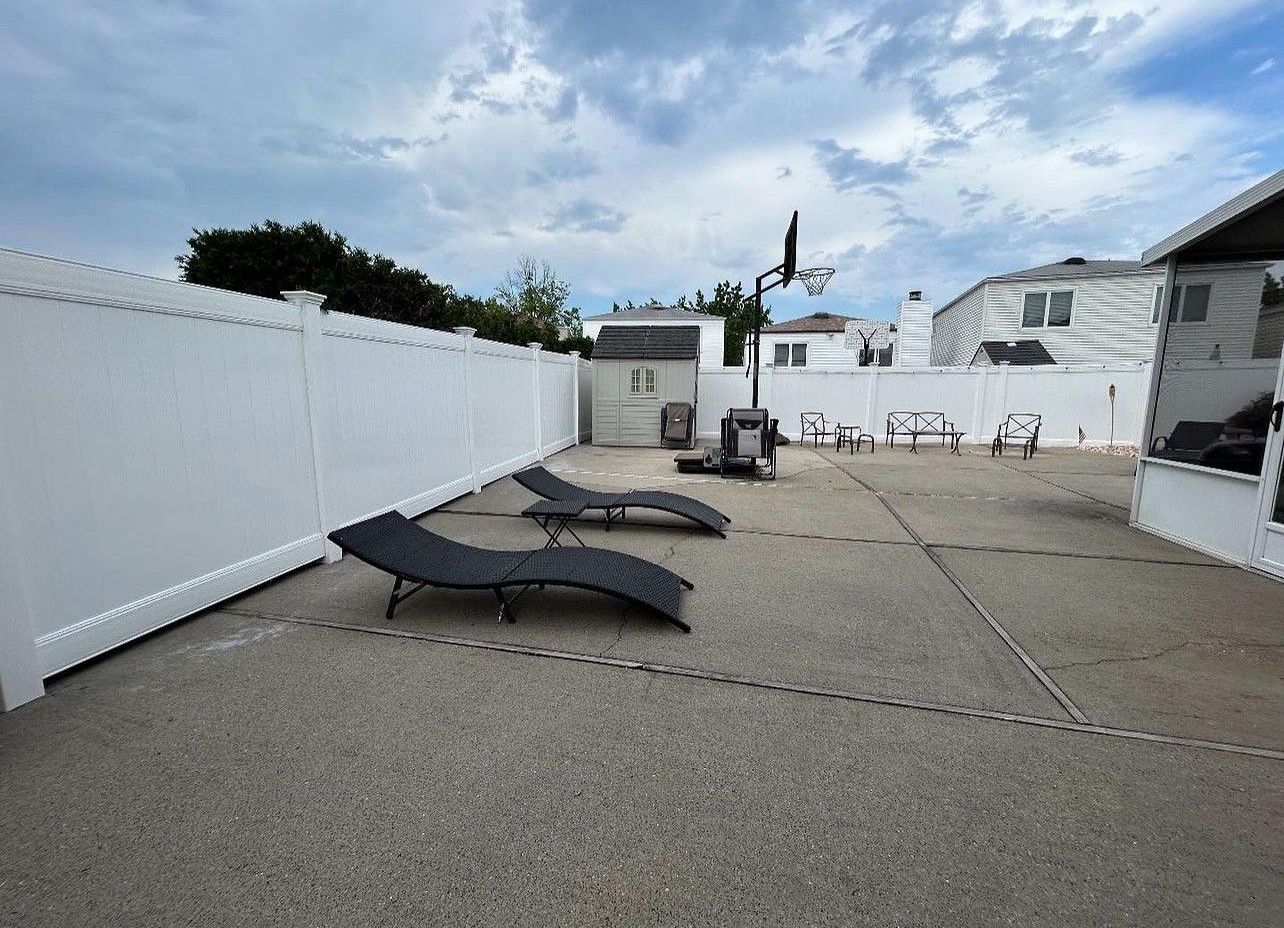 There are three lounge chairs in the backyard of a house.