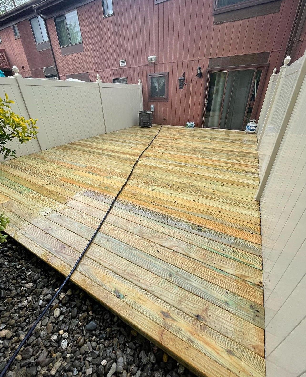 A wooden deck with a white fence in front of a house.