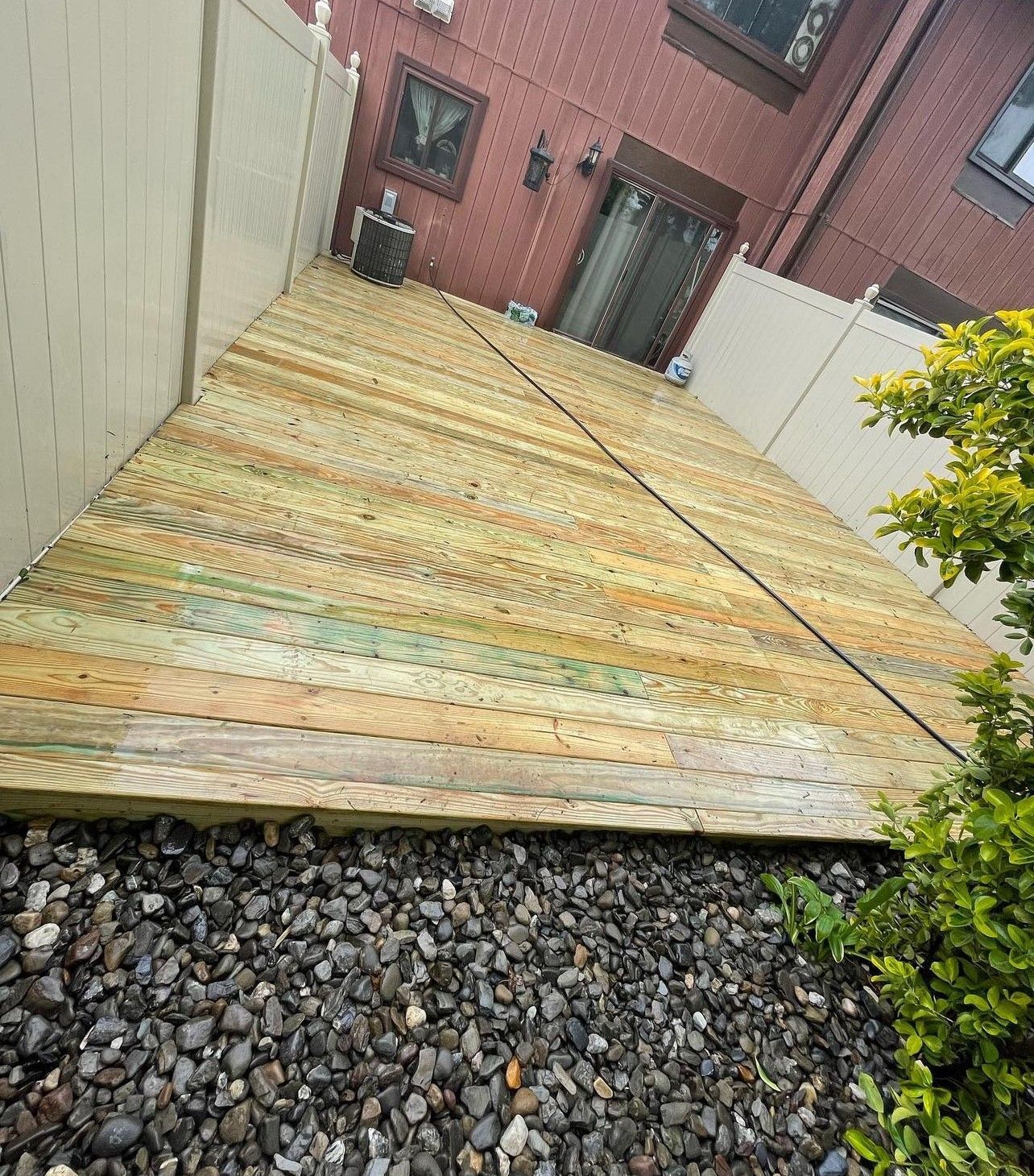 A wooden deck is sitting on top of a pile of gravel in front of a house.