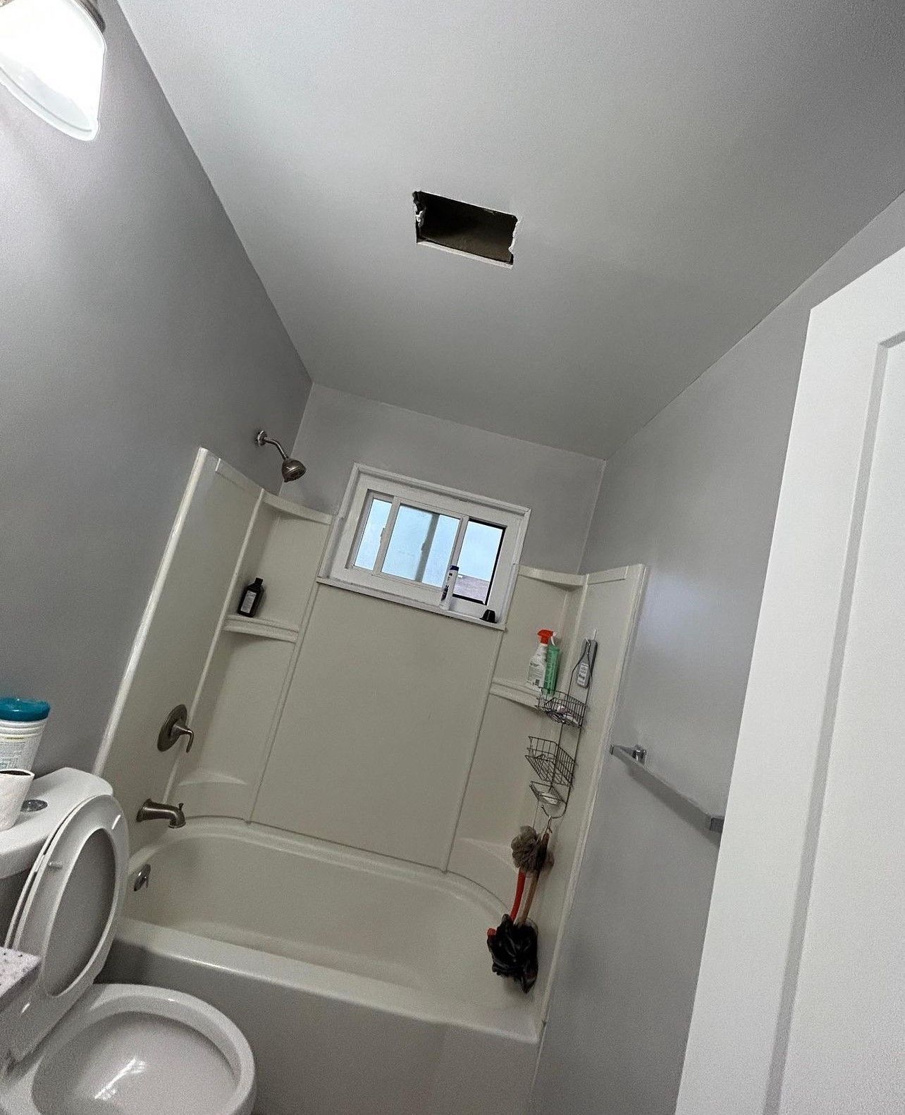 A bathroom with a toilet , tub , shower and window.