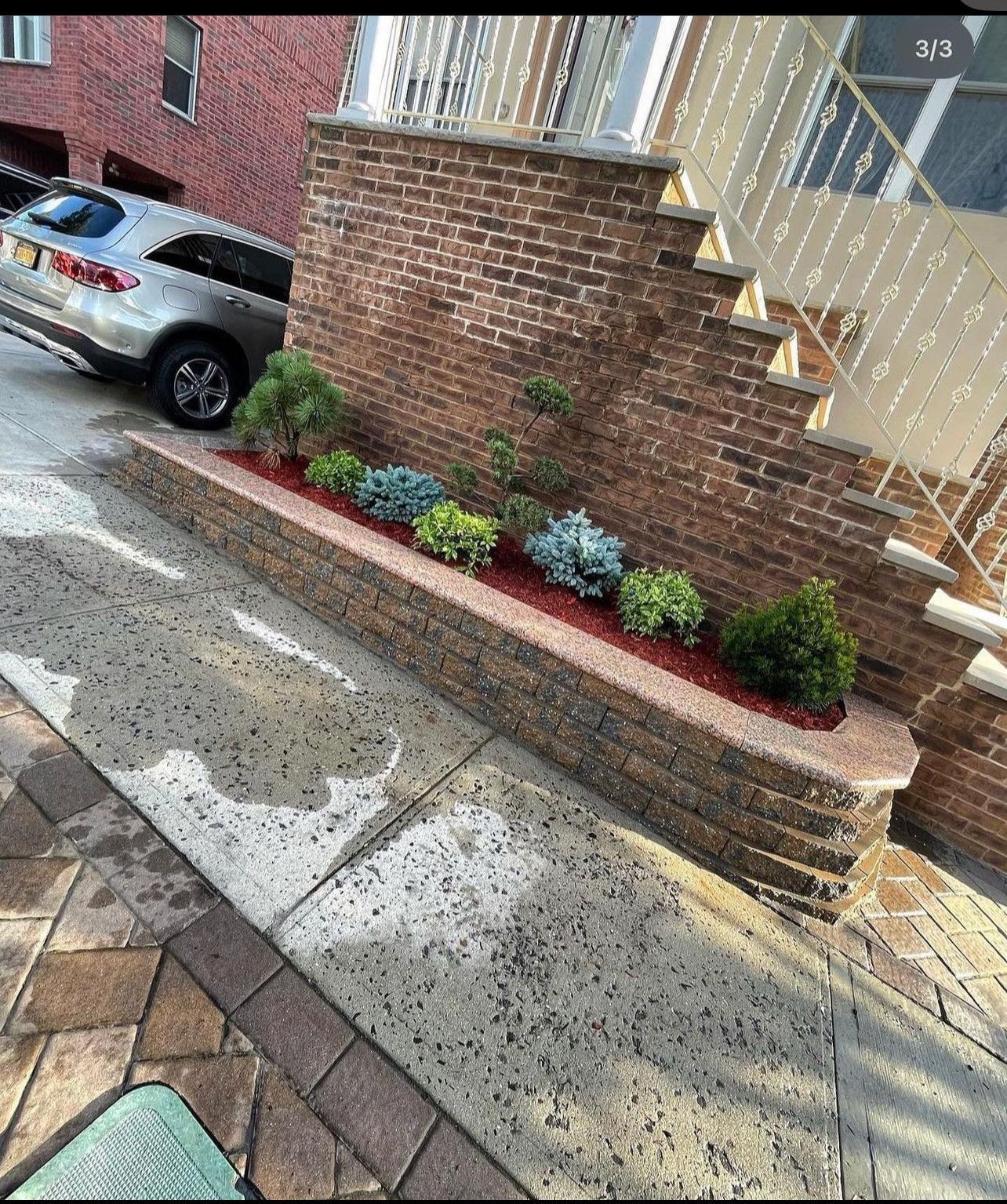 A car is parked in a driveway next to a brick wall.