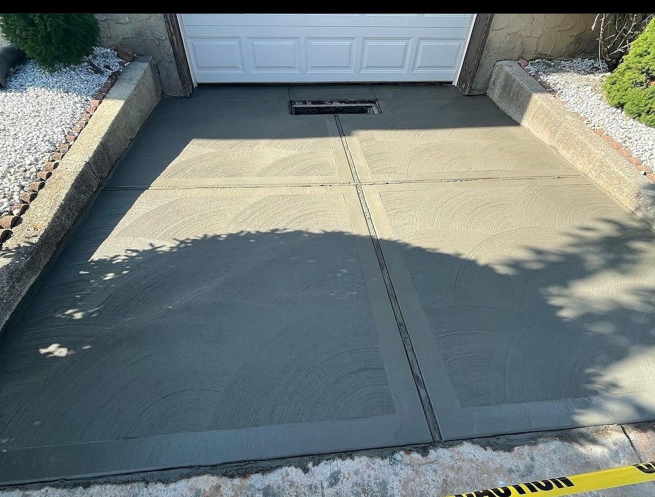 A concrete driveway is being built in front of a garage door.