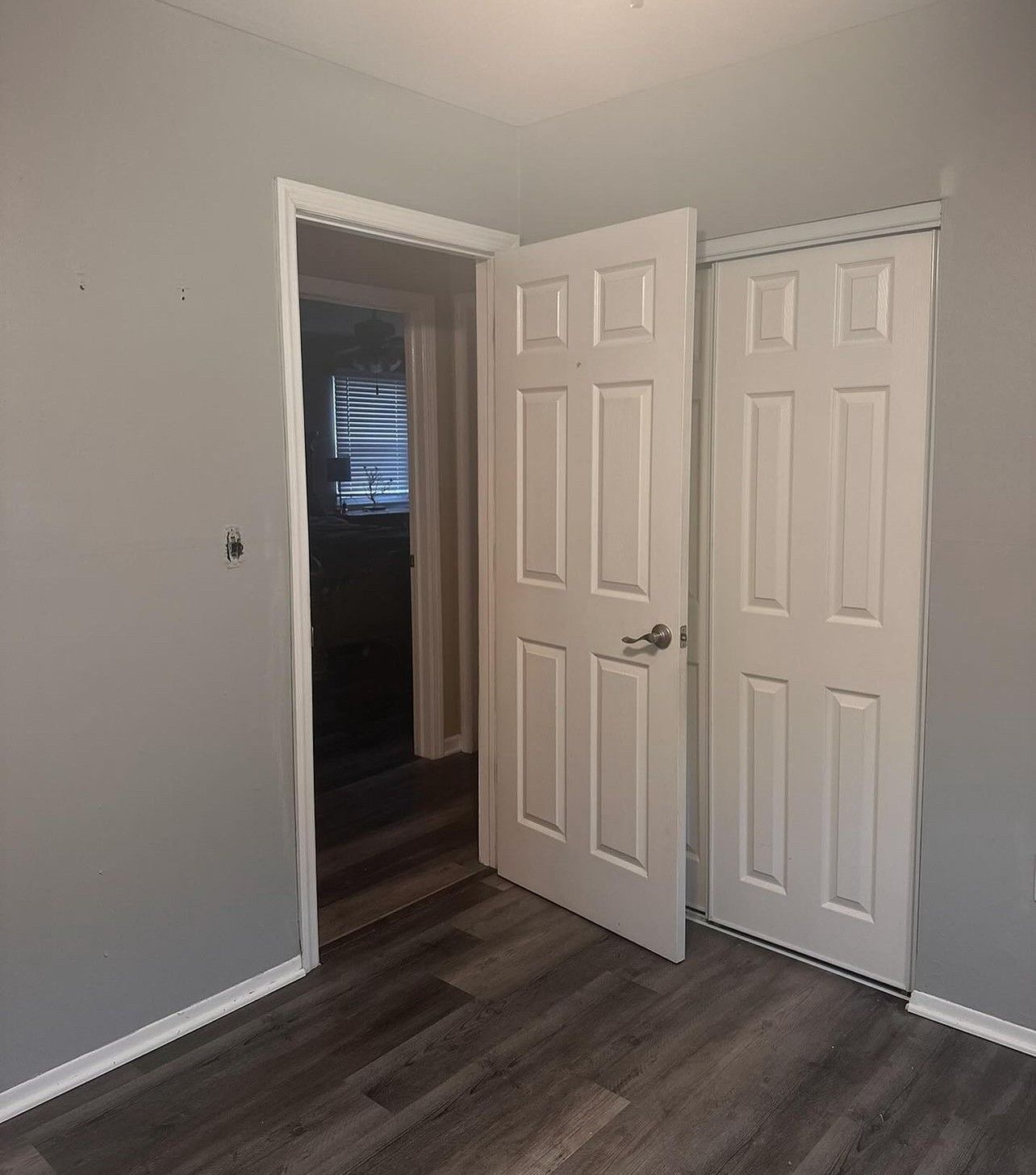 An empty room with two white doors and a wooden floor.