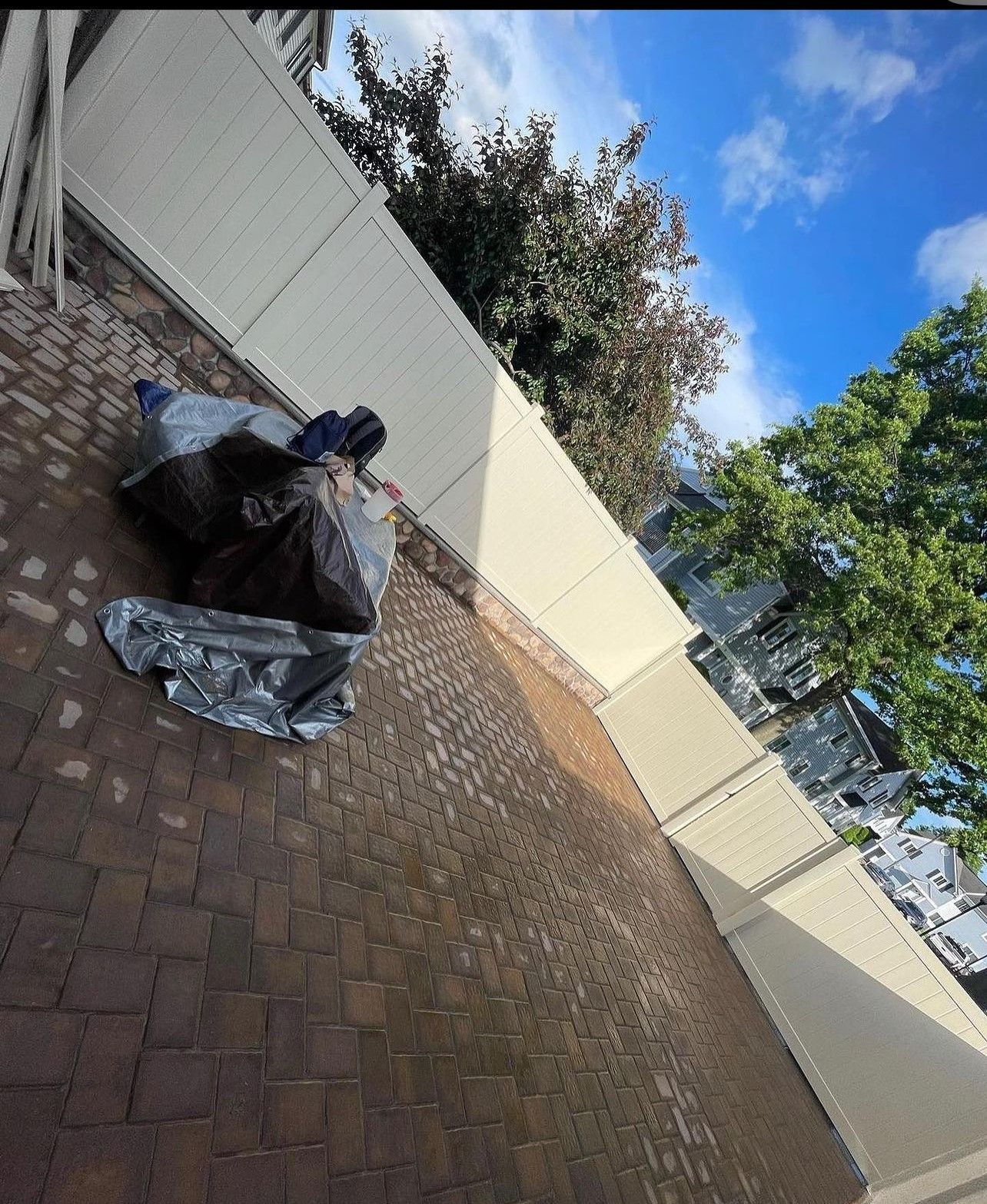 A motorcycle is sitting on a brick patio next to a white fence.