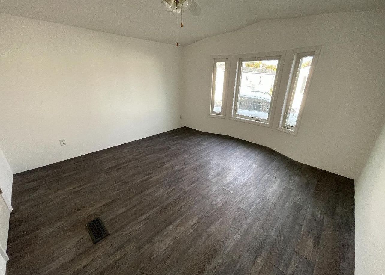 A large empty room with hardwood floors and white walls.