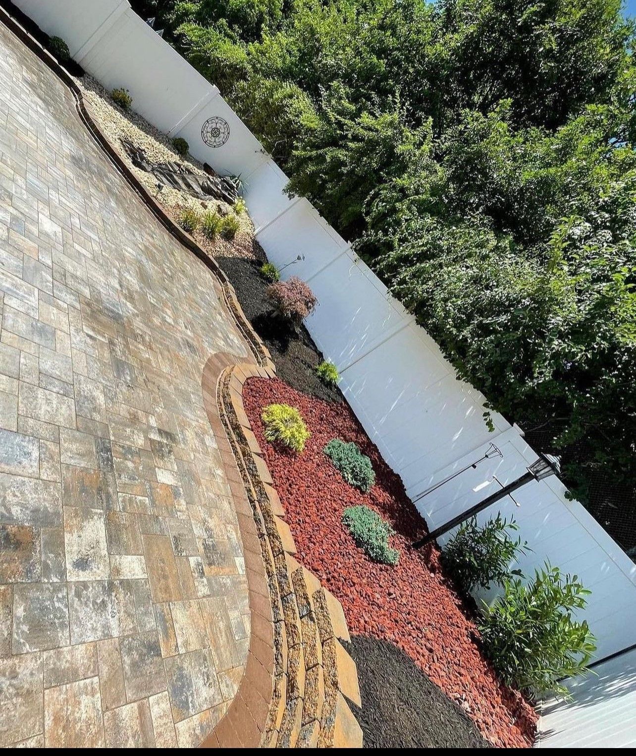 A white fence is surrounded by a lush green garden