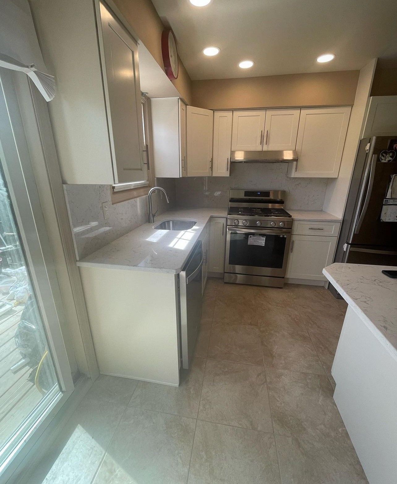 A kitchen with white cabinets , a stove , a sink , and a refrigerator.