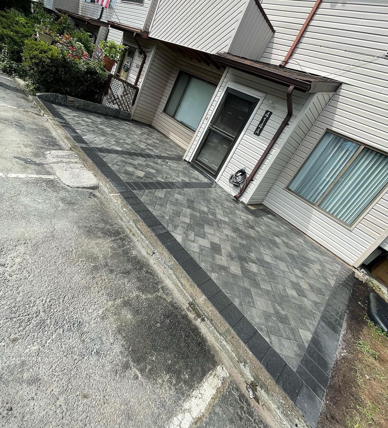 A house with a patio in front of it and a driveway leading to it.
