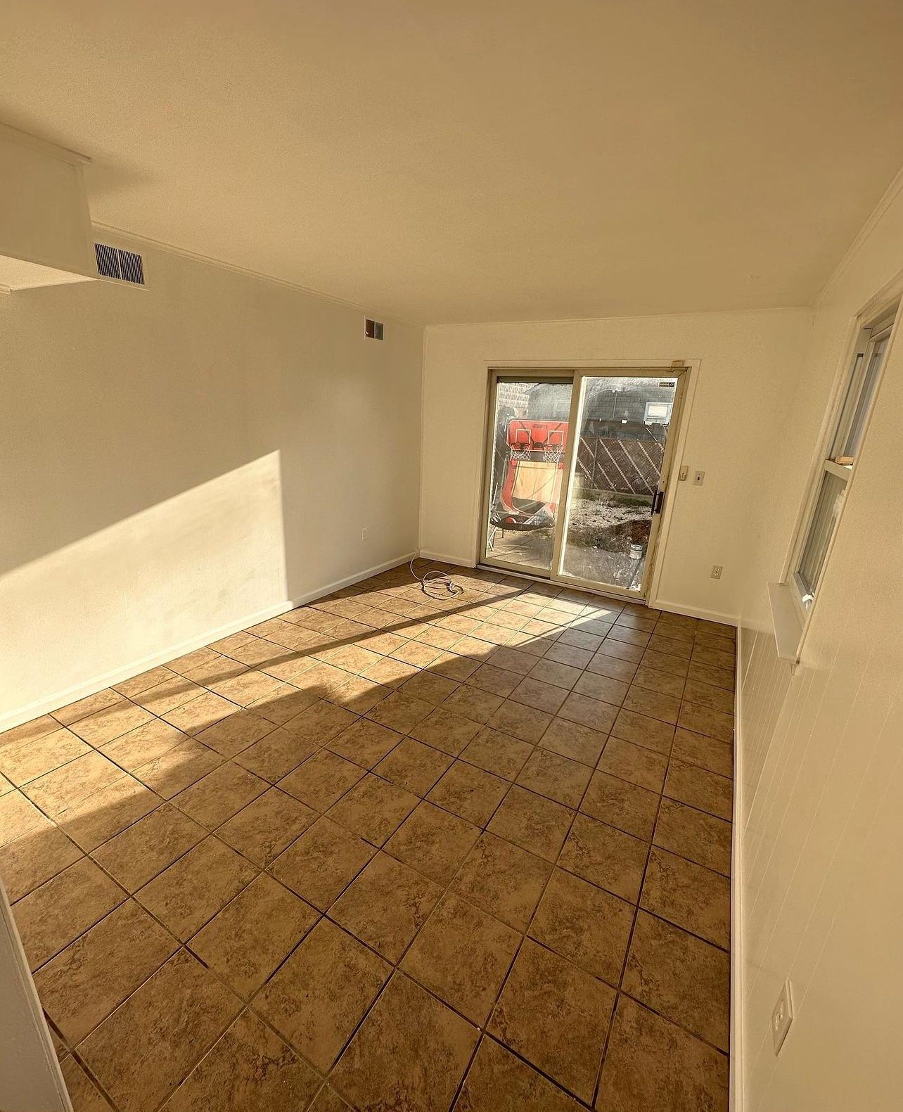 A living room with a sliding glass door and tile floor.
