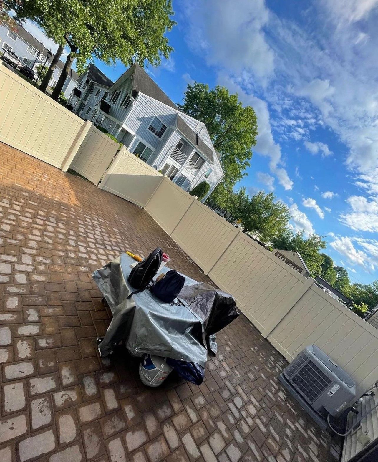 A motorcycle is parked on a brick driveway next to a fence.