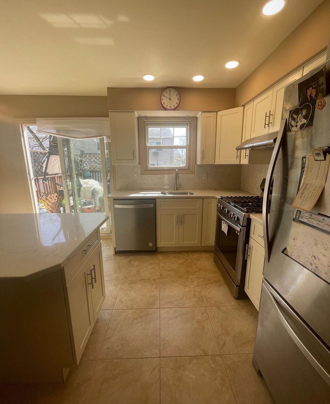 A kitchen with stainless steel appliances and a clock on the wall.