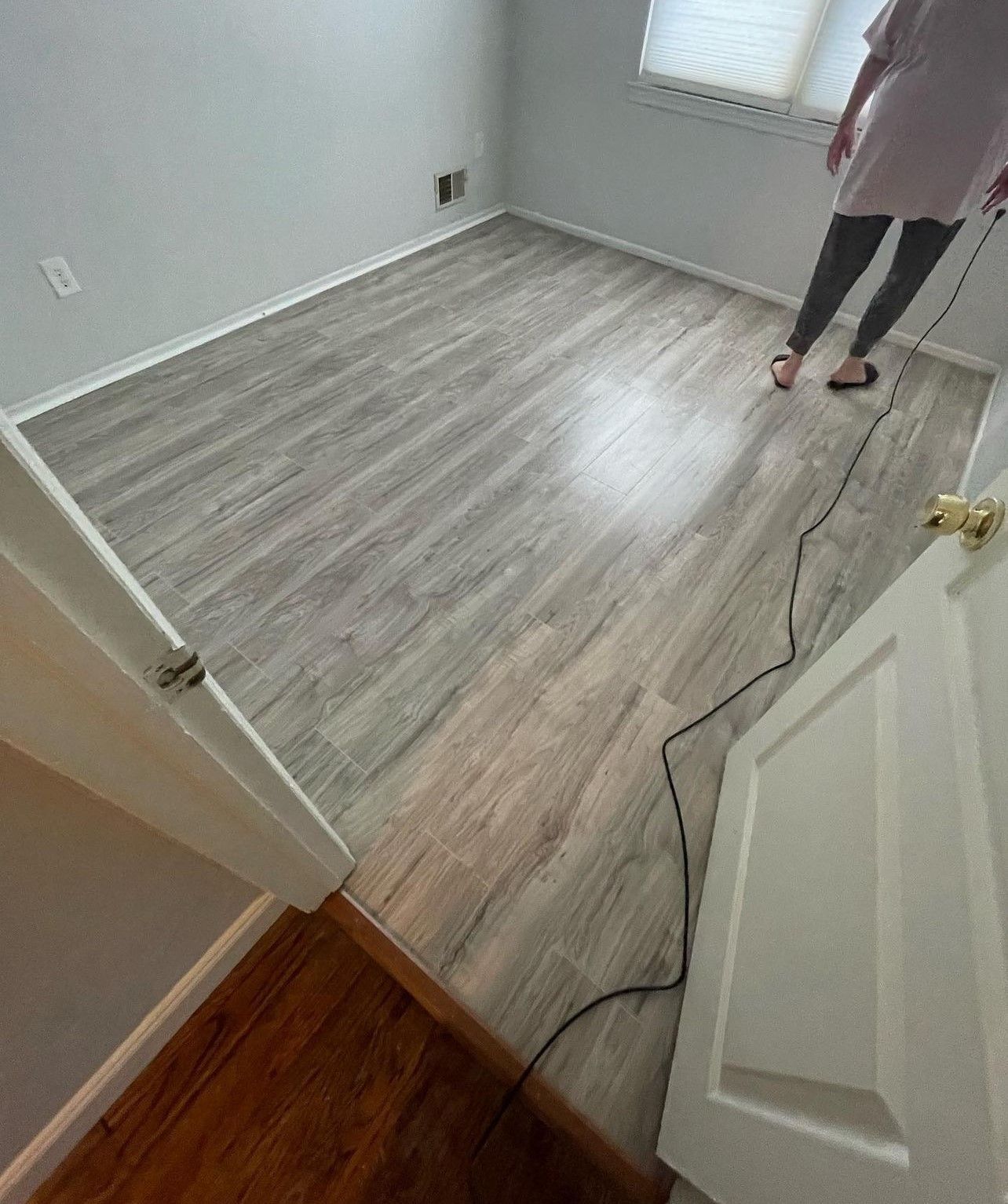A woman is standing in a room with a vacuum cleaner on the floor.
