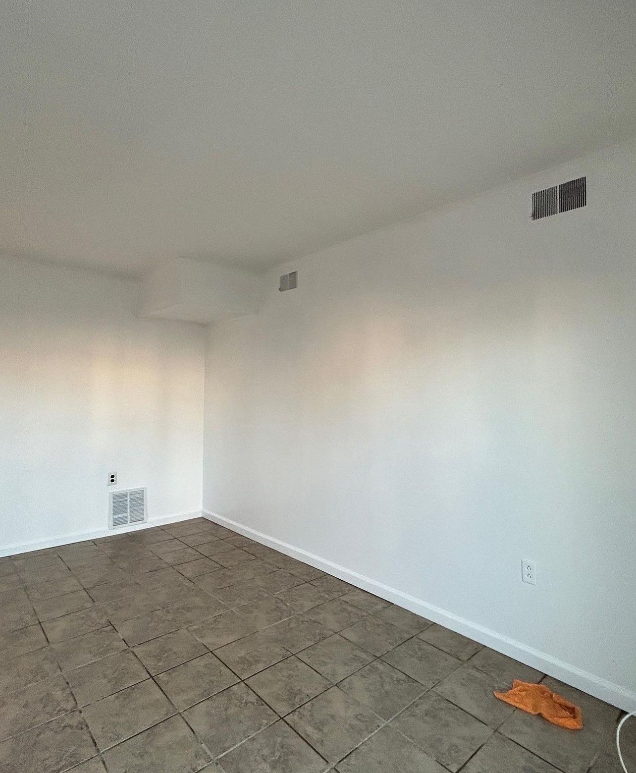 An empty room with tile floors and white walls.