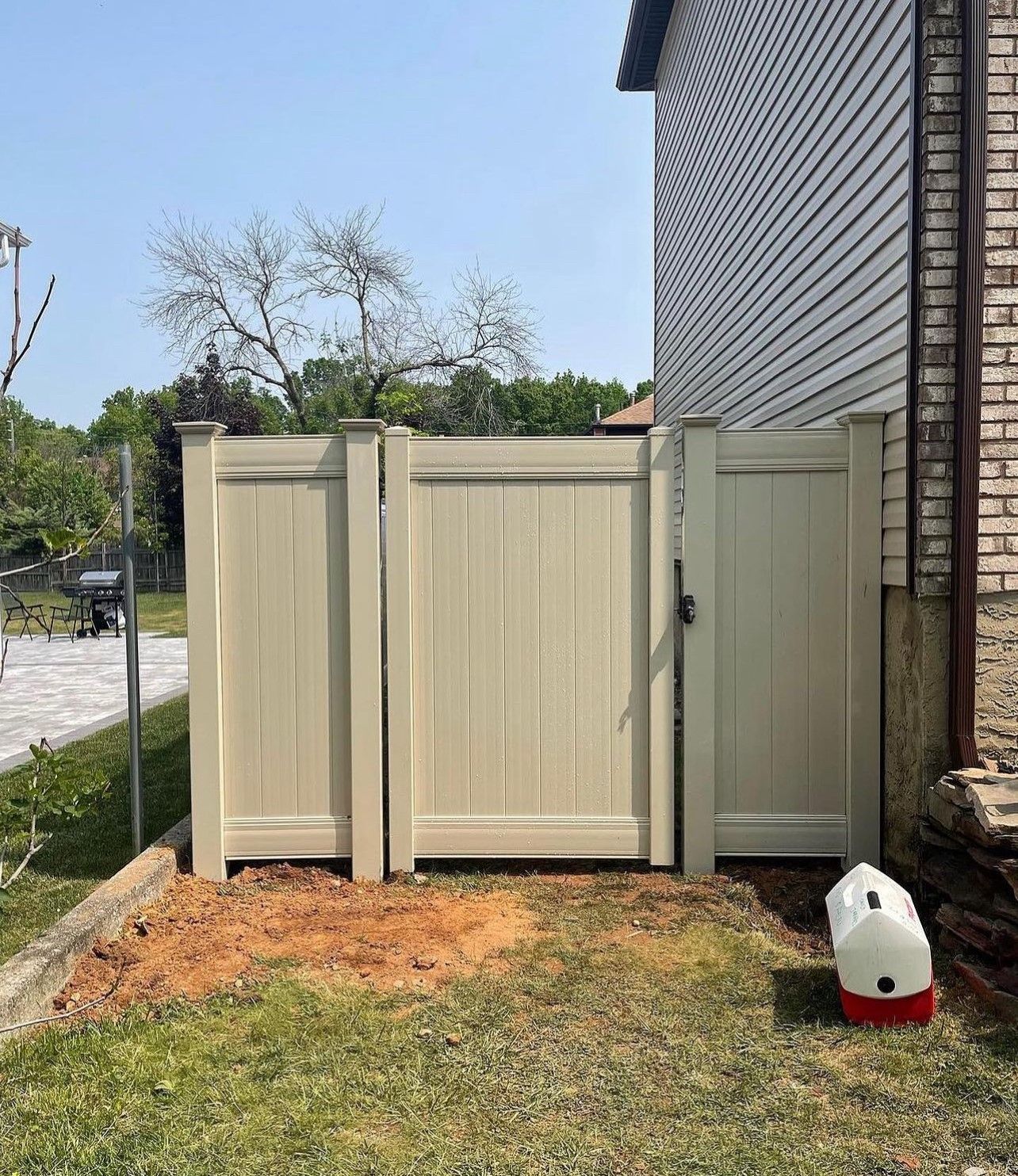 A white fence with a gate in front of a house.