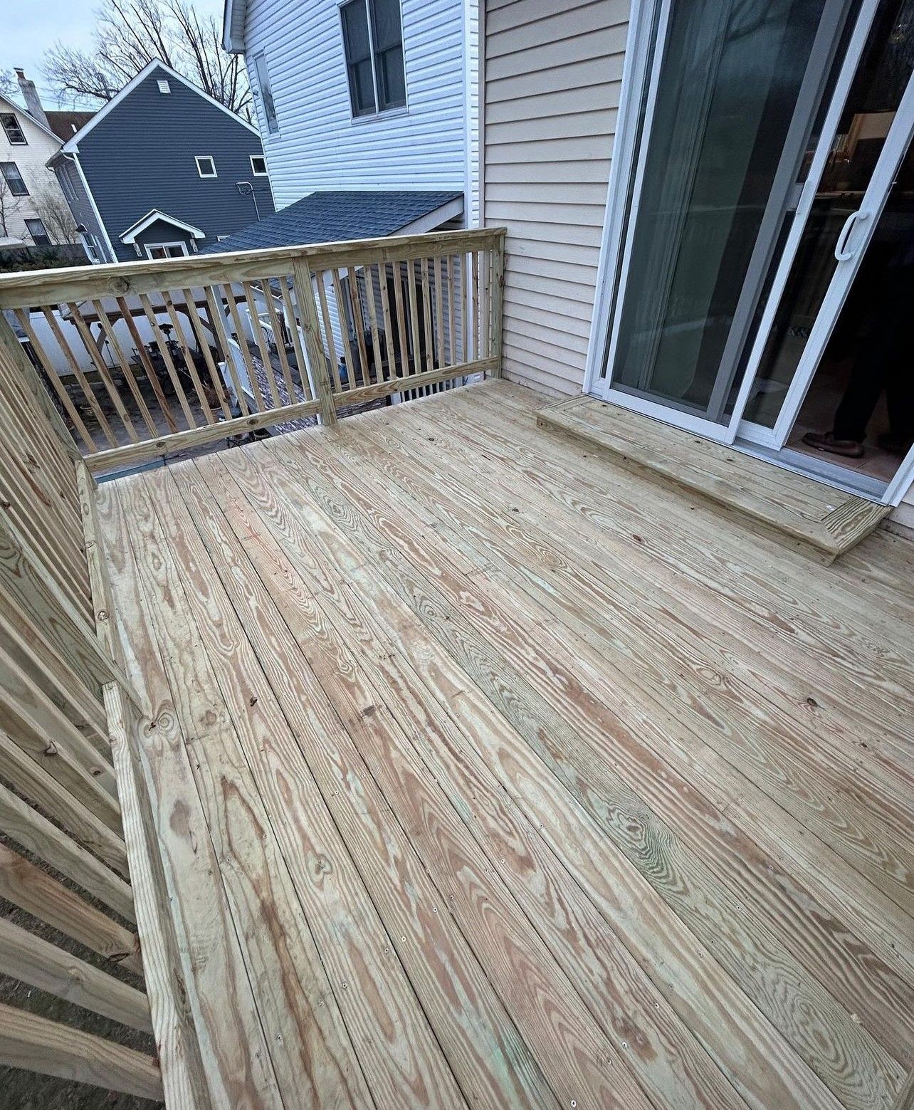 A wooden deck with a sliding glass door and railing.