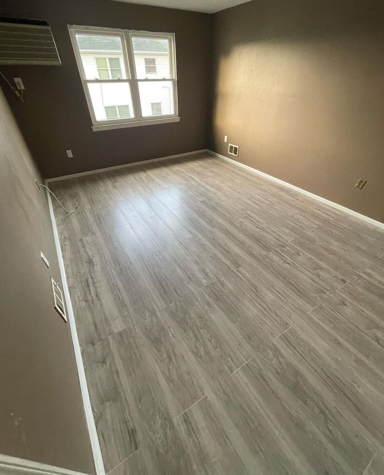 An empty room with hardwood floors and a window.