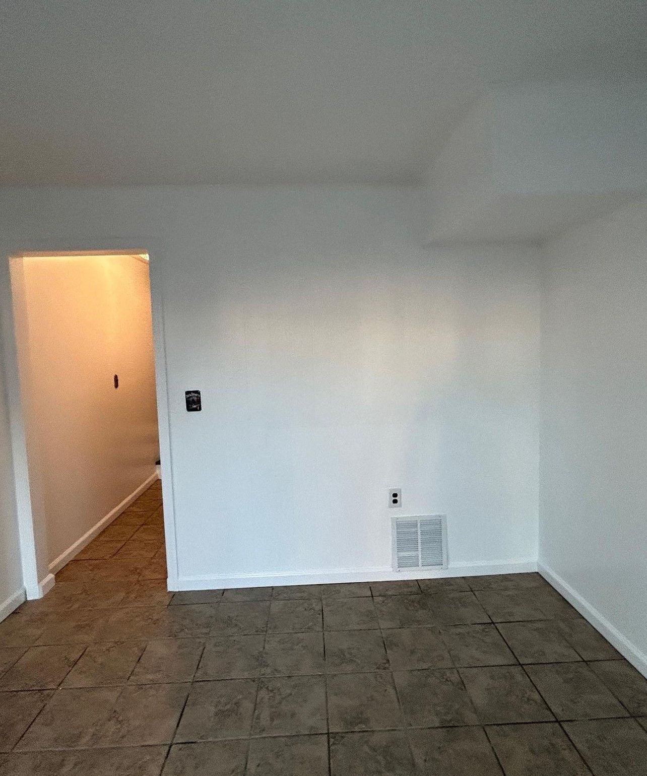 An empty living room with tile floors and white walls.