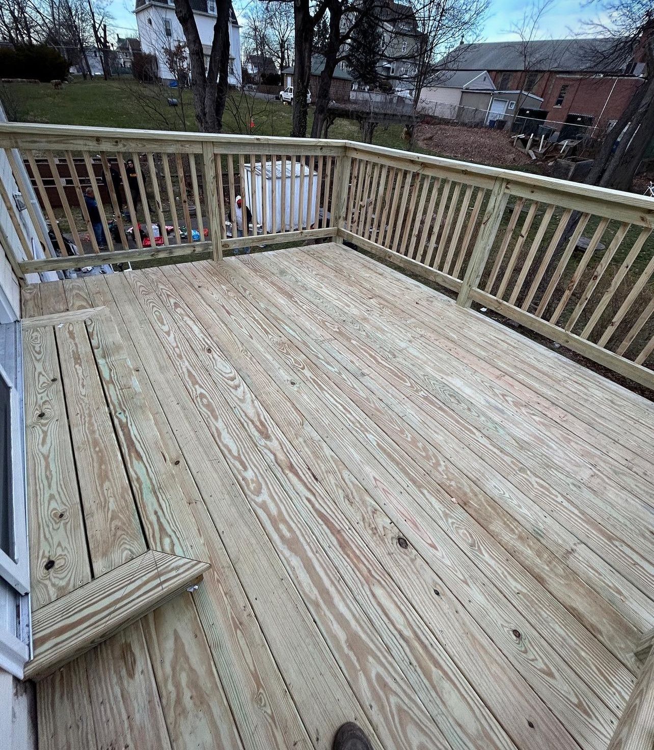 A person is standing on a wooden deck with a railing.