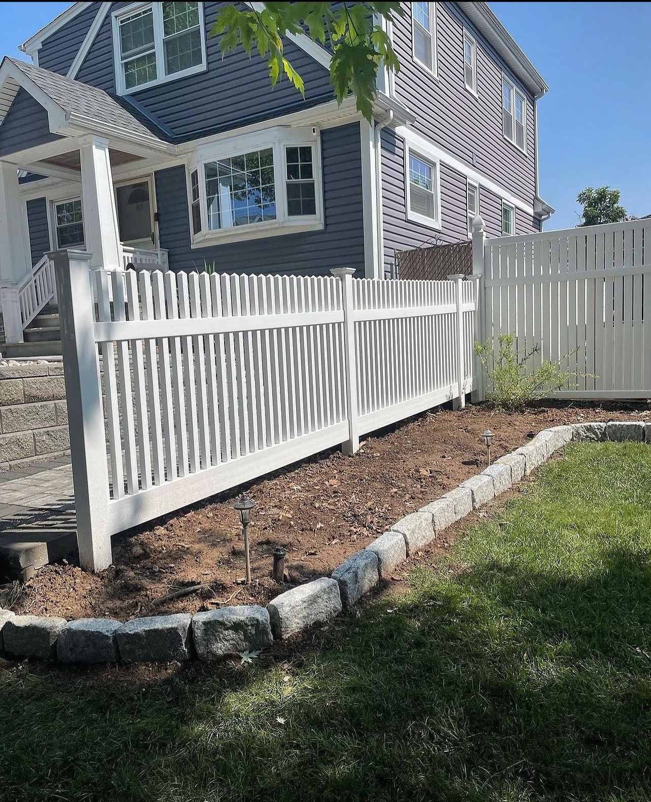 A white picket fence is in front of a purple house.