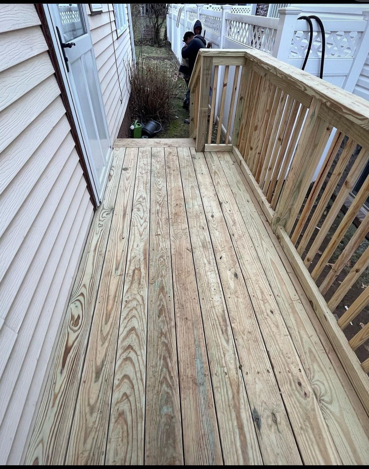 A man is standing on a wooden deck next to a house.
