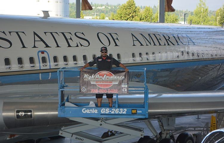 Man on lift in front of Air Force One, holding a banner;