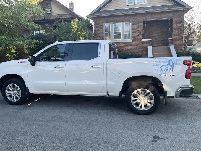 A white truck is parked in front of a brick house.