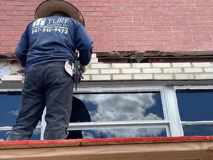 A man wearing a turf shirt is working on a window