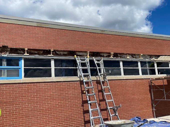 A ladder is sitting on the side of a brick building.