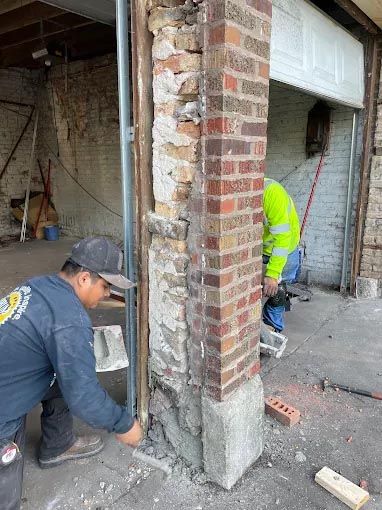 A man is working on a brick wall in a garage.