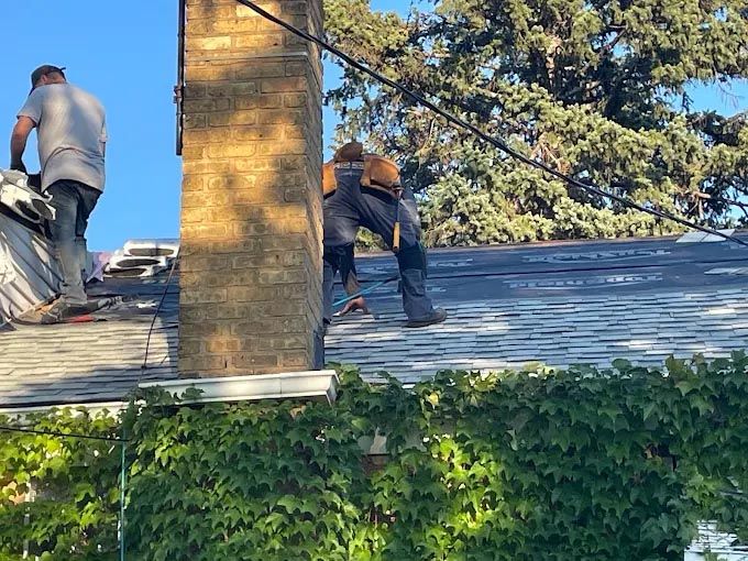 Two men are working on the roof of a house.