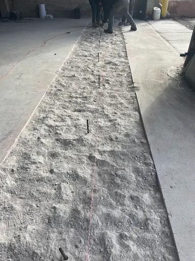 A group of people are working on a concrete driveway.
