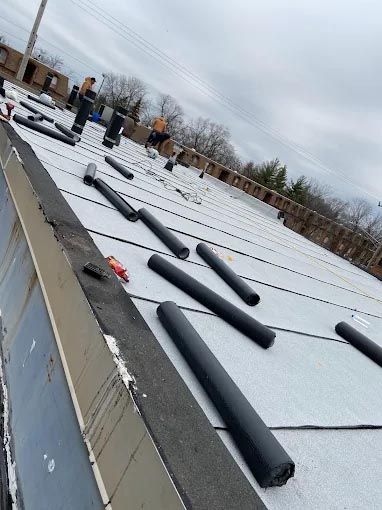 A roof with a lot of rolls of rubber on it.