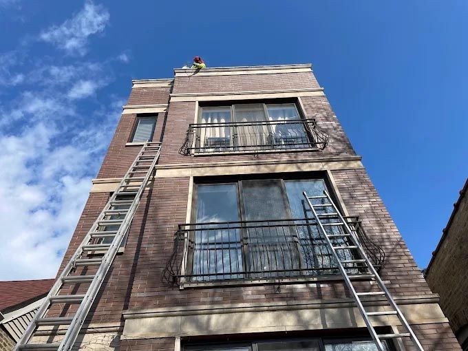 A man is standing on top of a tall building with a ladder.