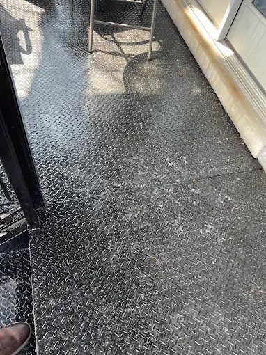 A person is standing on a black floor next to a chair.