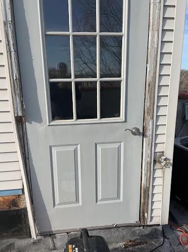 A white door with a window is sitting next to a shed.
