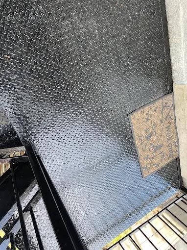 A close up of a metal floor with a staircase in the background.