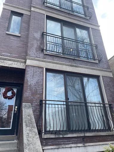 A brick building with a balcony and a wreath on the door.