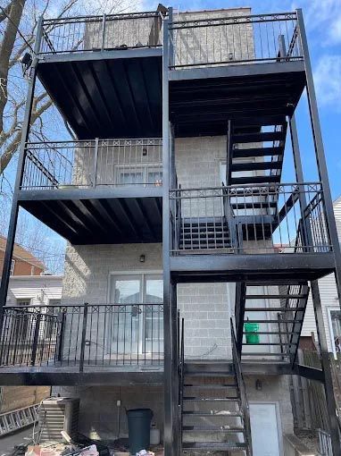 A building with a balcony and stairs on the side of it.